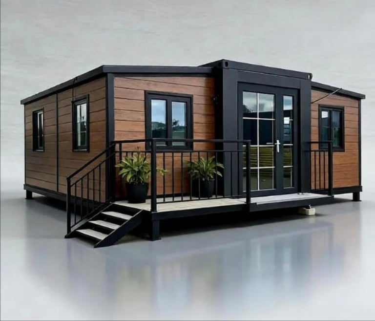 Modern tiny house with brown wood siding, black metal frame, and wraparound deck with stairs